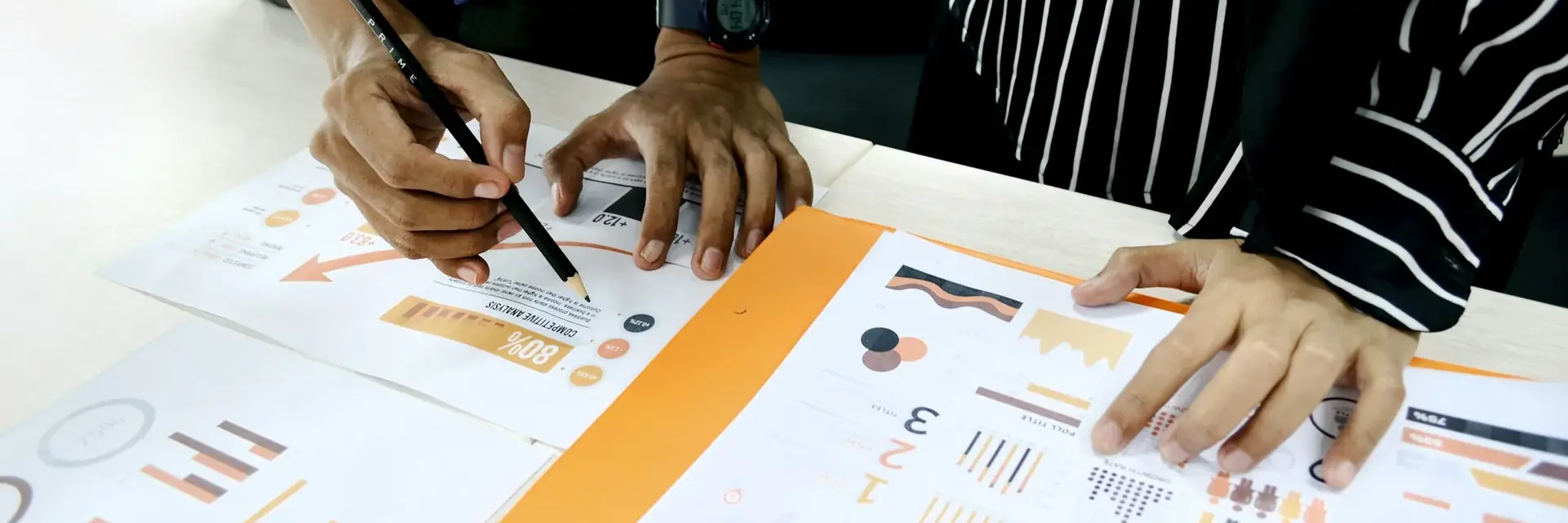 Manos señalando gráficos impresos sobre una mesa de trabajo