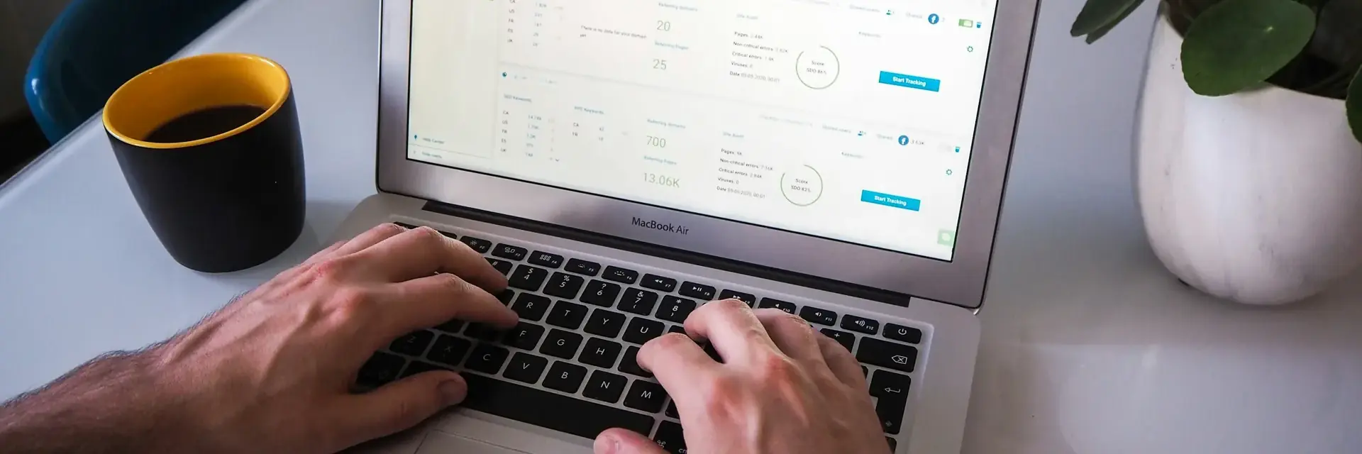 Manos en el teclado de un portátil con un panel de proyectos SEO en pantalla