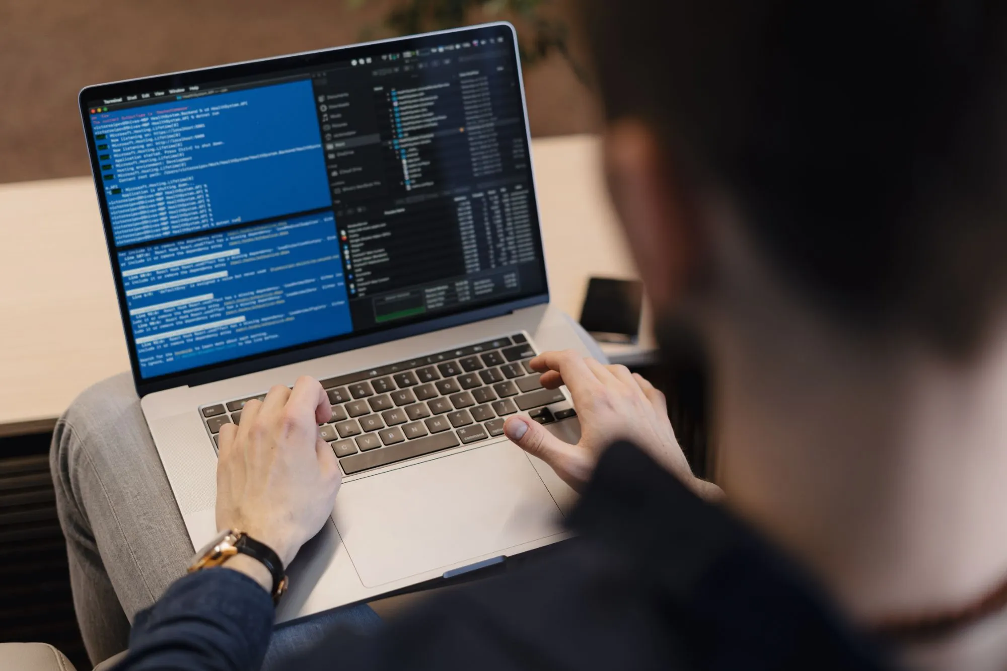 Hombre trabajando en un portátil con ventanas de código y archivos en pantalla
