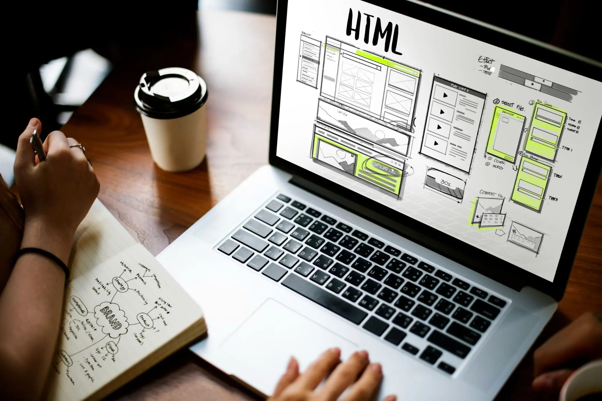 Portátil con un wireframe de página web HTML junto a un café y una libreta con un mapa mental