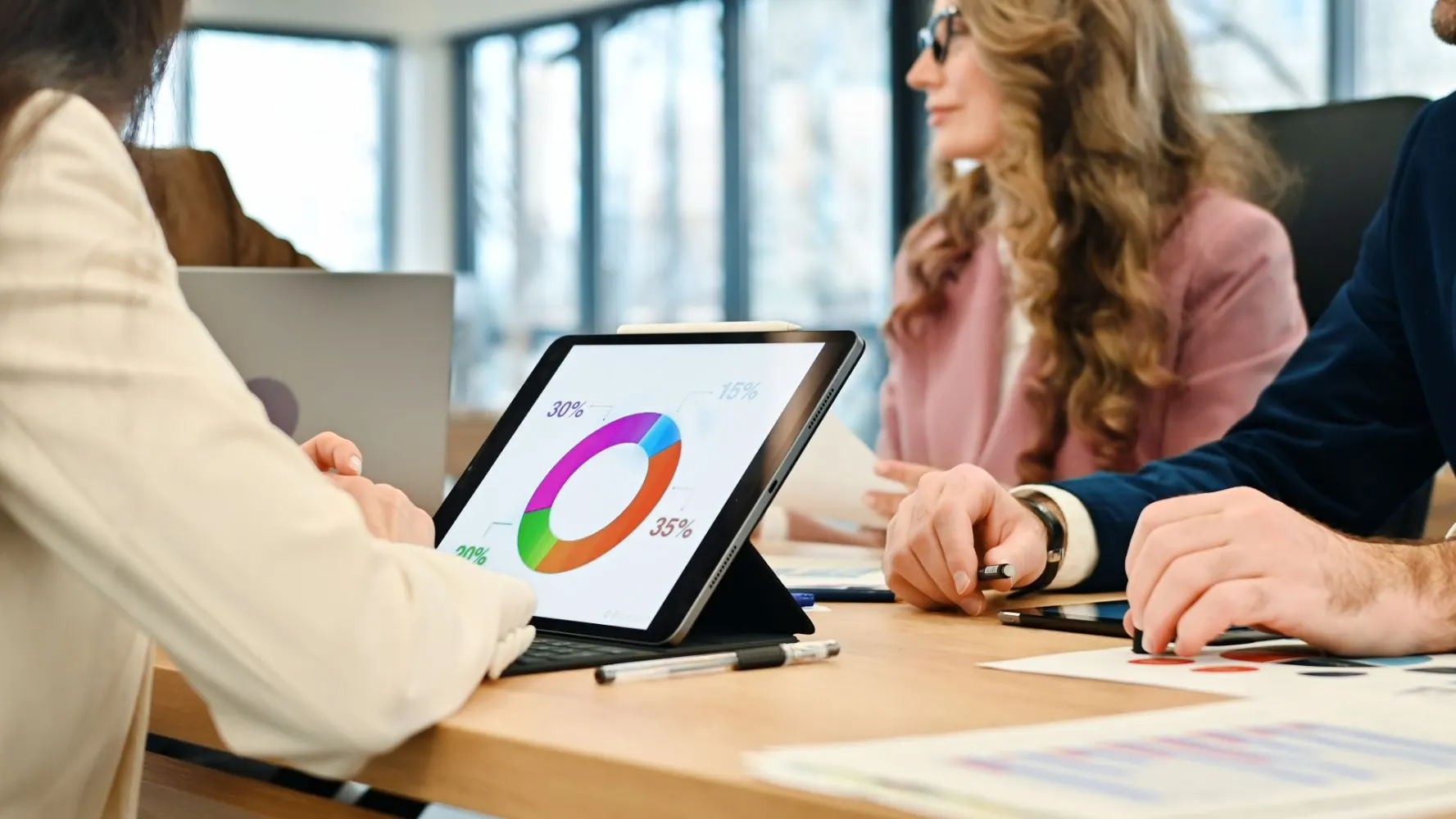 Reunión de trabajo con una tableta que muestra un gráfico circular de porcentajes