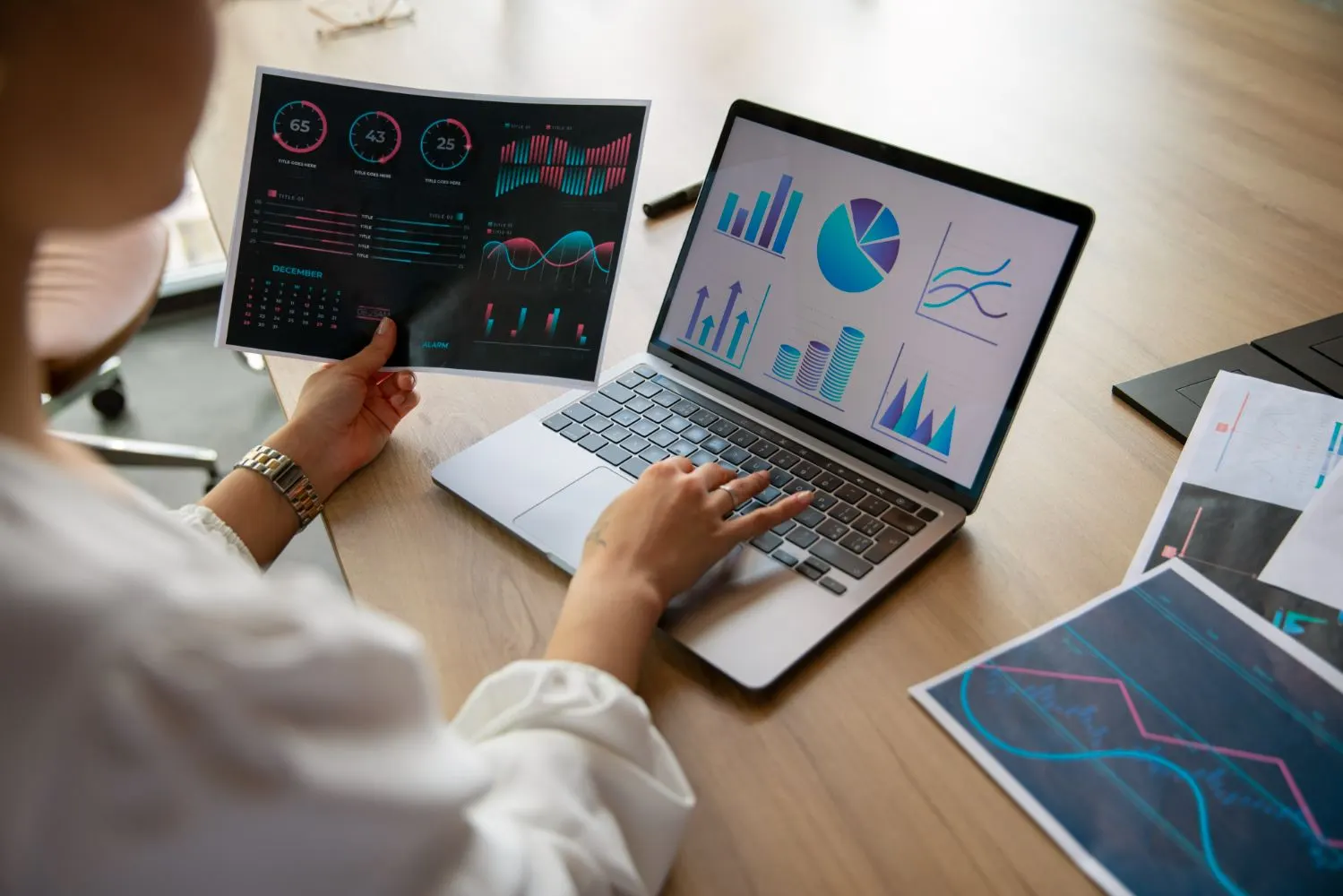 Mujer con un informe de datos en la mano usando un portátil con gráficos