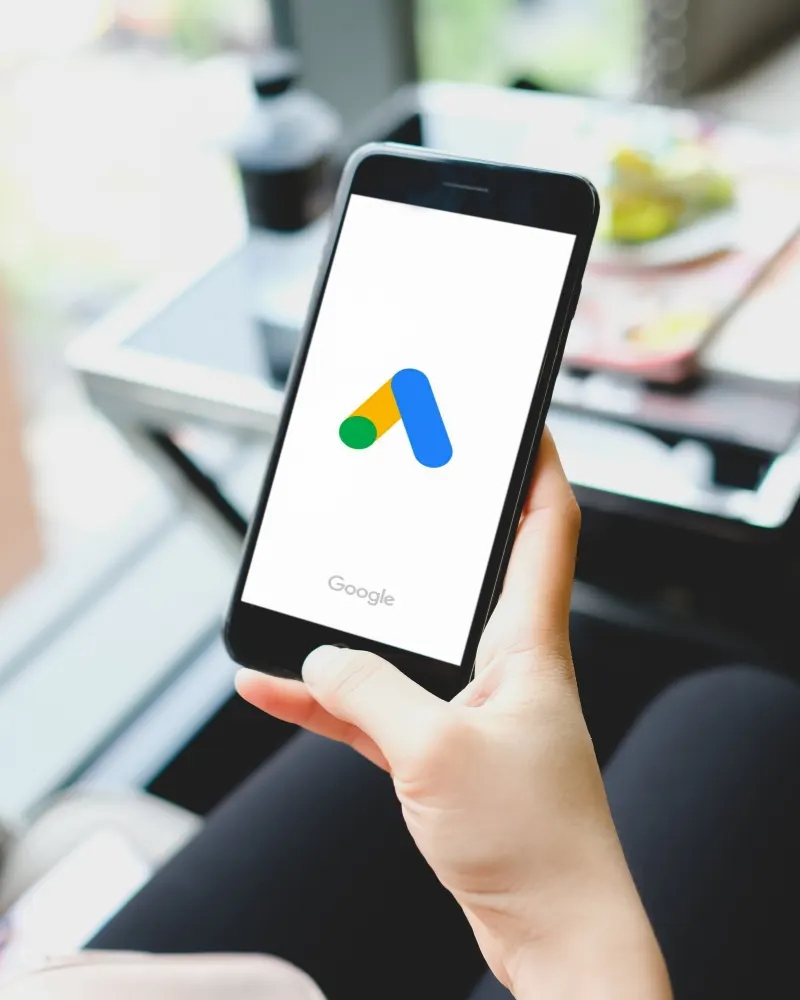 Mà sostenint un mòbil amb el logotip de Google Ads a la pantalla