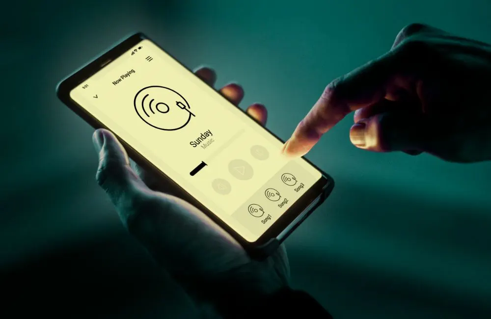 Manos usando una aplicación de música en un smartphone con la pantalla iluminada
