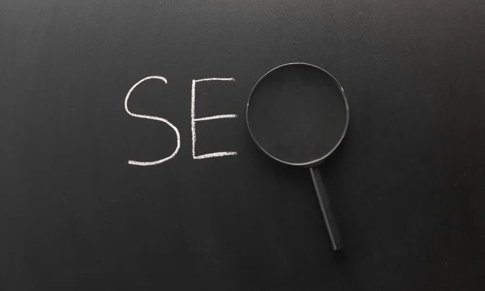 Palabra SEO escrita con tiza en una pizarra, con una lupa formando la letra O