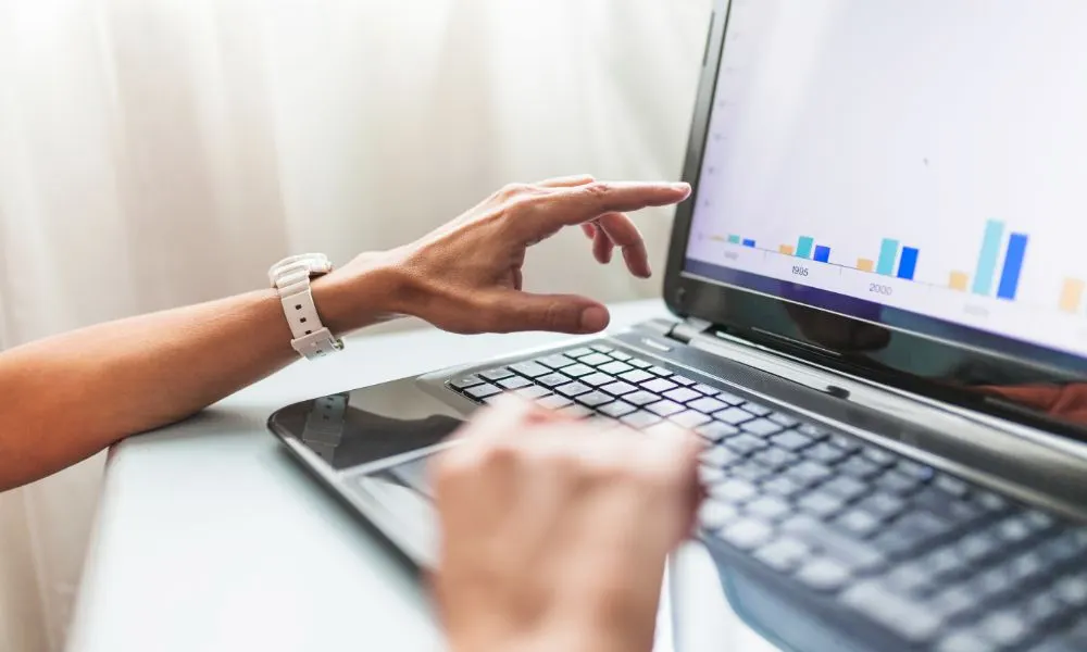 Mans assenyalant un gràfic de barres a la pantalla d’un portàtil