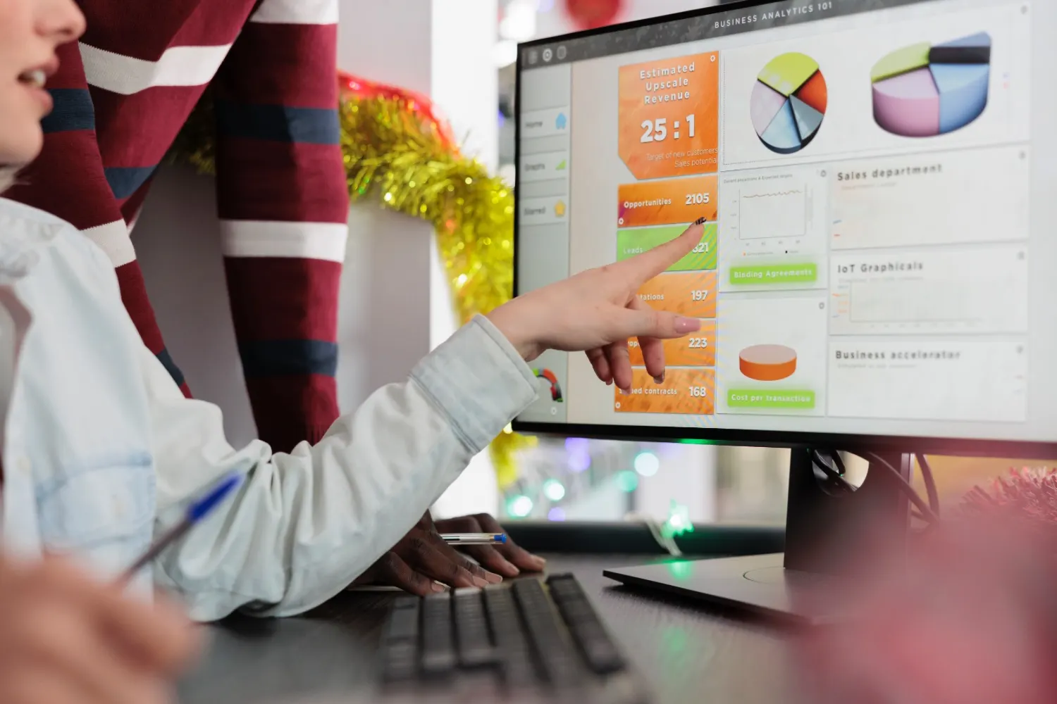 Persona señalando en un monitor un panel de analítica con métricas de ventas y gráficos