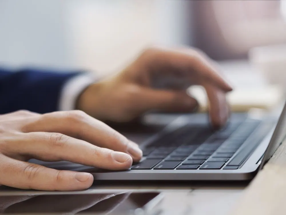 Primer plano de manos escribiendo en el teclado de un portátil