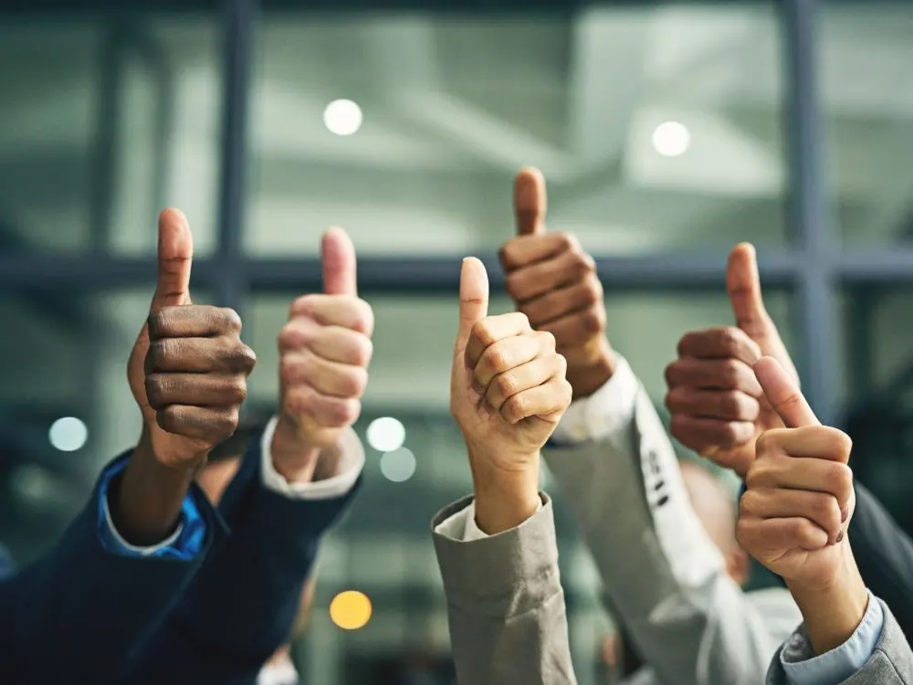 Varias manos de un equipo levantando el pulgar en señal de aprobación