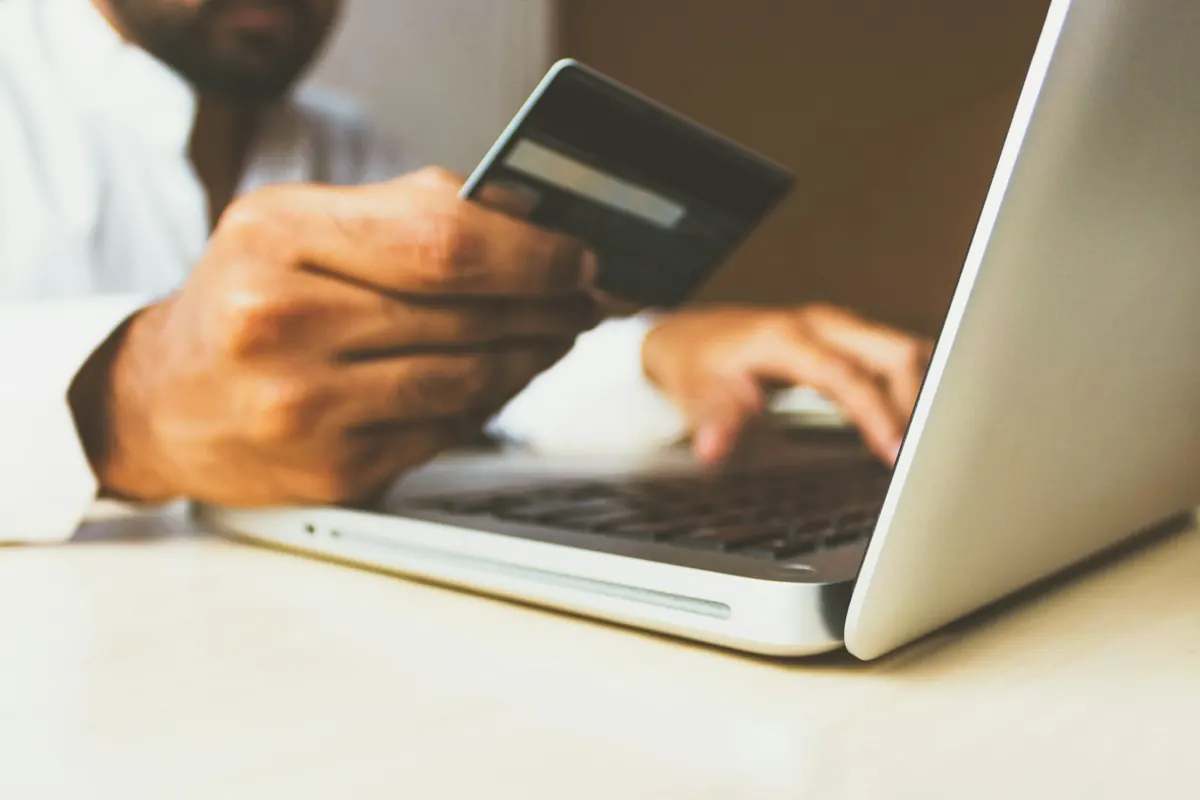 Persona comprando online con una tarjeta y un portátil